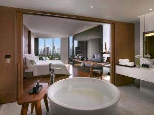 a bathroom with a bath tub and a bedroom at SO/ Bangkok in Bangkok