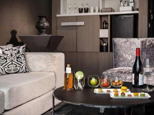 a living room with a couch and a table with wine bottles at SO/ Bangkok in Bangkok