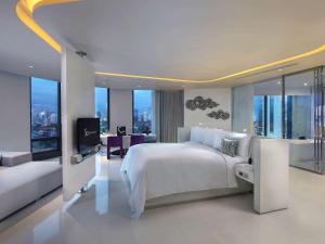 a white bedroom with a large bed and a television at SO/ Bangkok in Bangkok