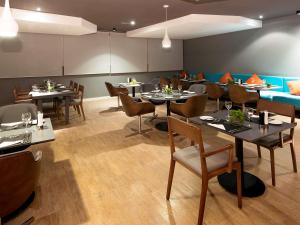 a restaurant with tables and chairs in a room at Novotel Santos Gonzaga in Santos