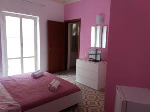 una camera rosa con letto e TV di A casa di Alba a Marsala