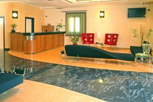 a lobby with a swimming pool and red chairs at Cerri Hotel in Castellammare del Golfo