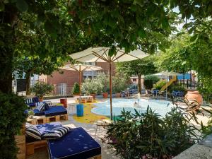 August Restaurant Hotel في Wolhusen: مسبح مع كراسي ومظلة في ساحة