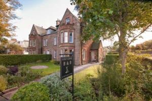 een groot bakstenen huis met een bord ervoor bij Golf Lodge Bed & Breakfast in North Berwick