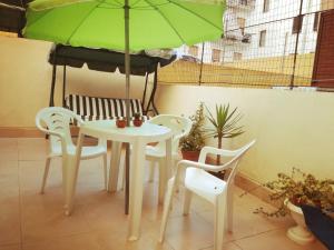 アルゲーロにあるNonna Ninaの白いテーブルと椅子(緑の傘付)