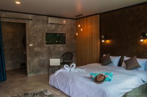 a bedroom with a large bed with a hat on it at Ongsa House in Bang Tao Beach