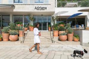 a woman walking a dog in front of a building at Adriana Hvar Spa Hotel in Hvar