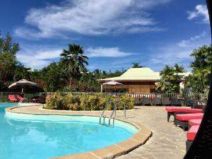 a swimming pool with tables and chairs in a resort at Résidence Le Vallon Guadeloupe Parc Piscine Appartements & Studios in Saint-François