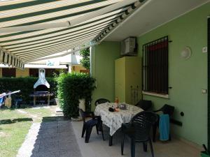 een patio met een tafel en stoelen onder een parasol bij Adriella apartments in Bibione