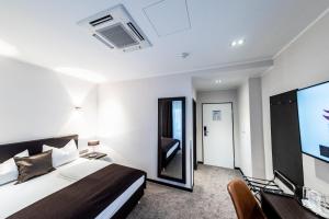 ein Schlafzimmer mit einem Bett und einem Flachbildfernseher in der Unterkunft Mauritius Hotel & Therme in Köln