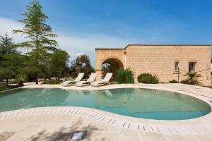 uma piscina com espreguiçadeiras e um edifício em Villa Satis by BarbarHouse em Casarano