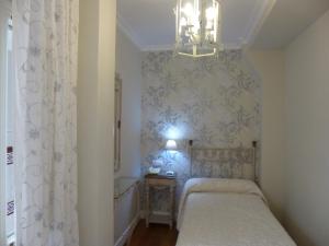 a small bedroom with a bed and a chandelier at Le Petit París in Seville