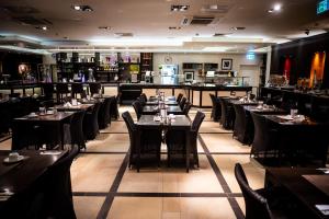 ein Restaurant mit Tischen und Stühlen und einer Bar in der Unterkunft Mauritius Hotel & Therme in Köln