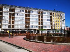 a large building with a fence in front of it at Duplex Tres Dormitorios Playa A Rapadoira in Foz