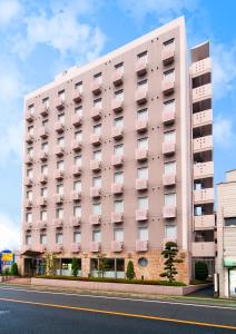 różowy budynek po stronie ulicy w obiekcie Super Hotel Matsuyama w mieście Matsuyama