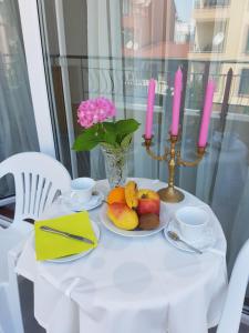 un tavolo bianco con un piatto di frutta e due candele di Guesthouse Zanier a Nesebar