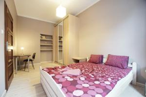 グダニスクにあるGdansk Apartmentのベッドルーム1室(紫とピンクのシーツが敷かれた大型ベッド1台付)