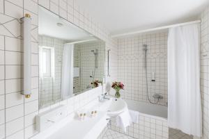 
a white bath tub sitting next to a white sink at Hotel Regina in Vienna
