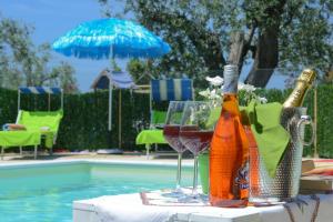 a table with a bottle and glasses next to a pool at villa la Scaletta in Alghero