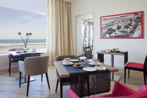 a dining room with tables and chairs and a view of the beach at Hotel & Spa Les Roches Noires in Les Sables-d'Olonne