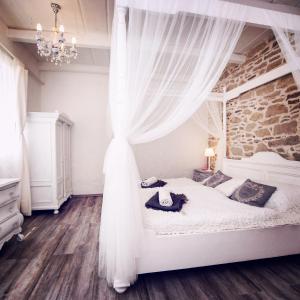 1 dormitorio con cama blanca con dosel y cortinas en Vidéki Varázs Vendégház en Bogács