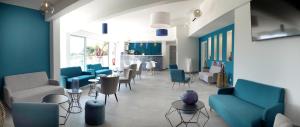 a waiting room with blue chairs and tables at Hotel La Voile in Bormes-les-Mimosas