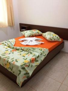 a bed with an orange blanket and pillows on it at Hotel Sarandi in Foz do Iguaçu
