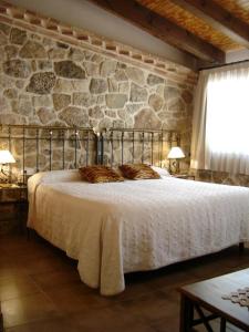 Hostal Casa Laure y Mª Jose في Arens de Lledó: غرفة نوم بسرير كبير وبجدار حجري