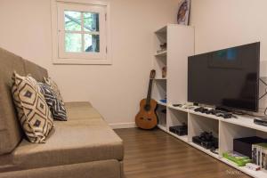 a living room with a couch and a television and a guitar at Kame House Hostel in El Nido