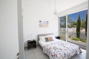 1 dormitorio con cama y ventana grande en Greco Villas, en Protaras