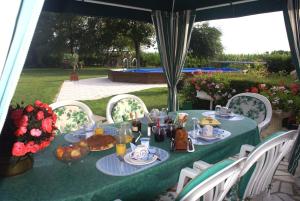 einen grünen Tisch mit Essen und Blumen darauf in der Unterkunft Villa Garnier in Saint-Michel-sur-Loire