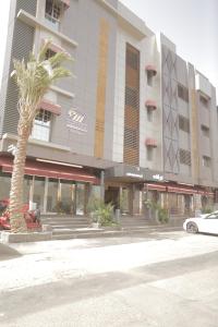 un edificio con una palmera delante de él en Niyaf Hotel Appartments, en Khamis Mushayt