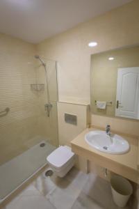 a bathroom with a sink and a toilet and a mirror at Apartamentos Las Rosas de Capistrano in Nerja