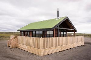 a building with a green roof and a wooden fence at Black Beach Cottage in Þorlákshöfn