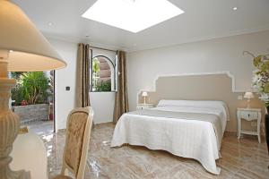 a white bedroom with a bed and a window at Le Magnolia in Calvi