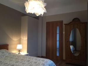 ein Schlafzimmer mit einem Bett, einem Spiegel und einem Kronleuchter in der Unterkunft Apartaments Selga in Roja