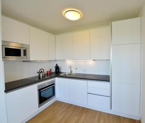 eine Küche mit weißen Schränken und einer Spüle in der Unterkunft Erdberger Lände in Wien
