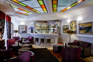 a bar in a room with a fireplace and chairs at Grand Hotel des Terreaux in Lyon