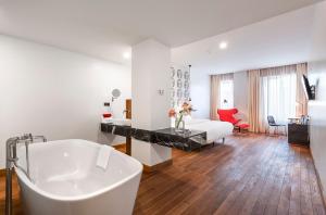 a white bathroom with a tub and a bedroom at Shota @ Rustaveli Boutique Hotel in Tbilisi City