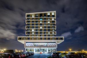 een hoog gebouw met auto's geparkeerd op een parkeerplaats bij Van Der Valk Luxembourg Arlon in Arlon