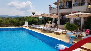 a swimming pool with chairs and umbrellas next to a building at Brilliant Aparthotel in Sozopol
