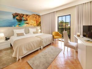 a bedroom with a large bed and a desk and a tv at Lagos Atlantic Hotel in Lagos