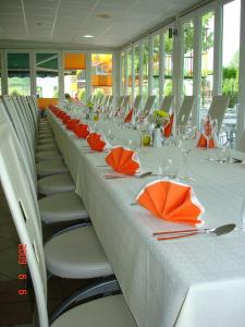 a long table with orange napkins and chairs in a room at Rooms Hochkraut in Celje