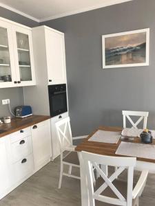 kuchnia z białymi szafkami oraz stołem i krzesłami w obiekcie Apartament z widokiem na jezioro w Rydzewie