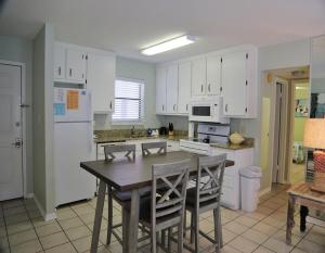 eine Küche mit weißen Schränken sowie einem Tisch und Stühlen in der Unterkunft Southern Sands 104 Condo in Gulf Shores