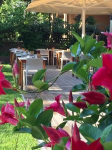 un giardino con tavoli, sedie e fiori rosa di Hotel Parco a Milano Marittima