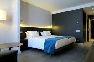 a hotel room with a large bed and a table at Hg City Suites Barcelona Apartments in Barcelona