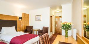 a hotel room with a bed and a vase of flowers at Three Counties Hotel in Hereford