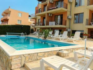 a swimming pool with white chairs and a building at Villa Iztok in Sozopol