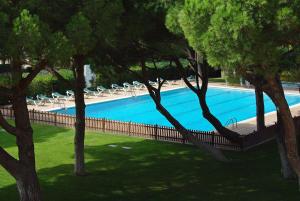 una piscina con sillas y árboles en un parque en Apartaments Beach & Golf Resort, en Pals